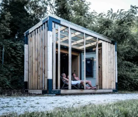 Side view of Pixxla Sauna at Zobor Lake and its covered terrace in nature.