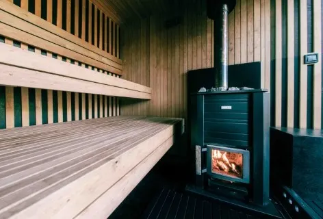 Empty interior of Pixxla Sauna at Zobor Lake with benches and a wood-burning stove.